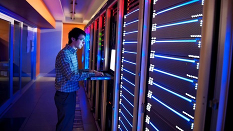 worker typing in information on large computer boards